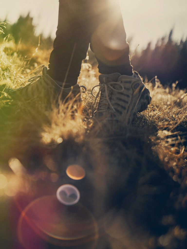 Wandernde Schritte im warmen Gegenlicht als Symbol für Weitergehen, Selbstführung und innere Orientierung.